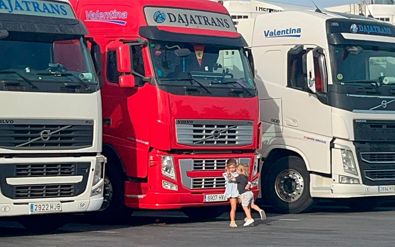 Imagen de varios camiones de Dajatrans con dos niñas abrazándose